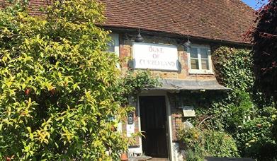 The exterior of a country pub with ivy covered walls and plants