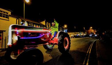 Chichester Christmas Charity Tractor Run | Tractor illuminated with lights driving at night through West Sussex