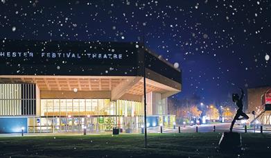 Image of the Chichester Festival Theatre at night with snow falling.