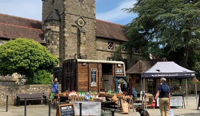 A picture showing a pop up farm shop in a horsebox next to a church