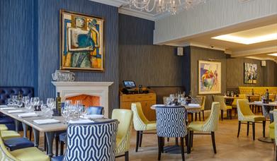 A bright dining room with blue and yellow chairs and decor