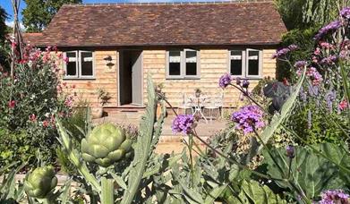 A view of a cabin with flowers and trees