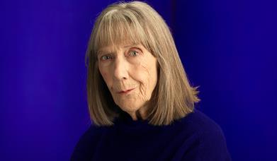 Eileen Atkins looks at us with a slight smile, wary and quizzical. She has light brown shoulder-length hair, blue eyes and is wearing a dark jumper.