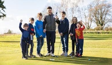 children and instructor on a golf course