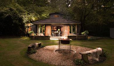 Exterior nighttime view of the cosy Cabin from across the garden, showing the fire pit